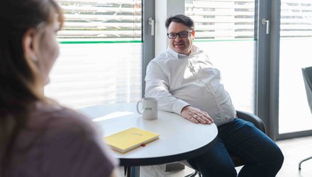Zwei Personen sitzen an einem Tisch in einem Besprechungsraum