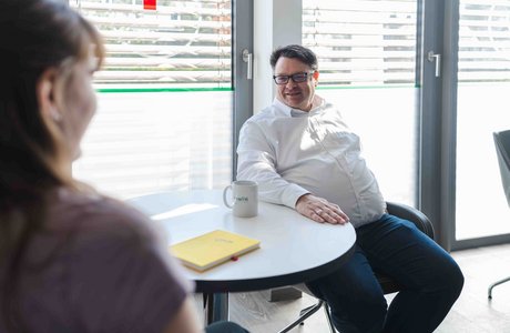 Zwei Personen sitzen an einem Tisch in einem Besprechungsraum