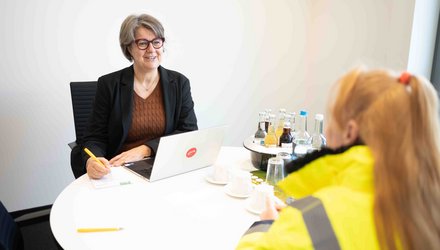 Zwei Personen sitzen an einem Tisch in einem Besprechungsraum
