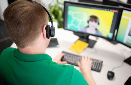 Ein Mitarbeiter hat einen Videocall mit einer Kollegin.