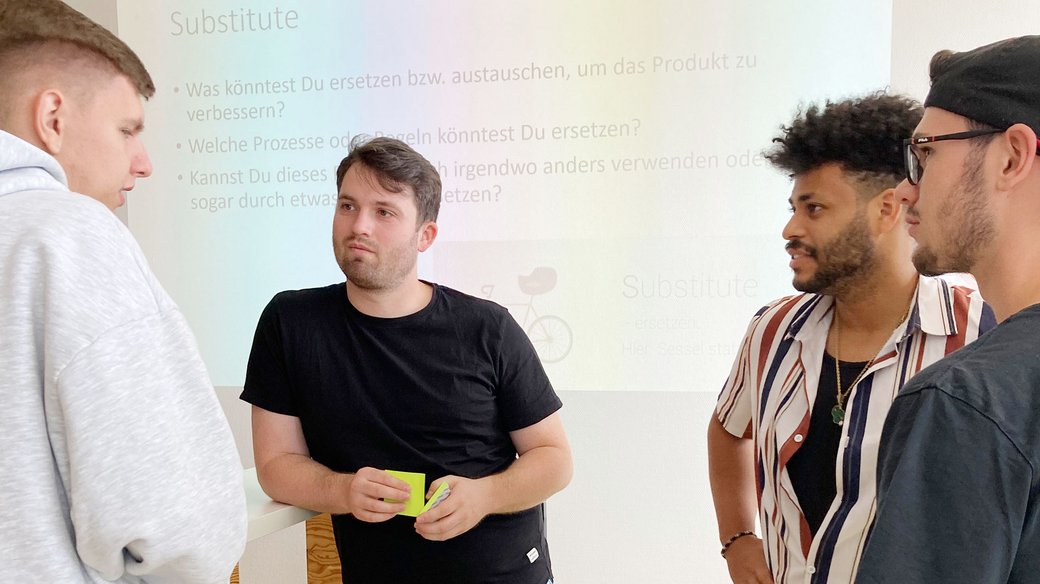 Vier Mitarbeitende diskutieren gemeinsam nach einem Vortrag