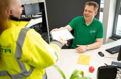 Ein Mitarbeiter der NOSTA Group übergibt einer Kollegin ein Dokument zum abzeichnen.